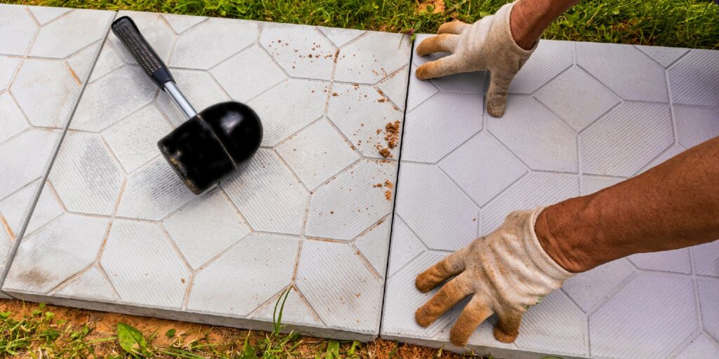 the hands of a worker in gloves lay tiles in a country house, cottage