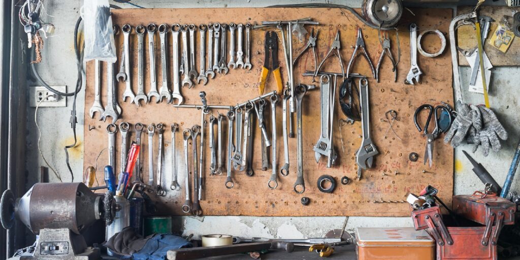 Old tools hanging on wall in workshop , Tool shelf against a wall